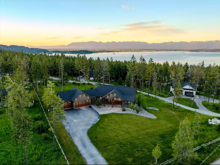 Aerial sunset view of the home with Flathead Lake and the mountains behind