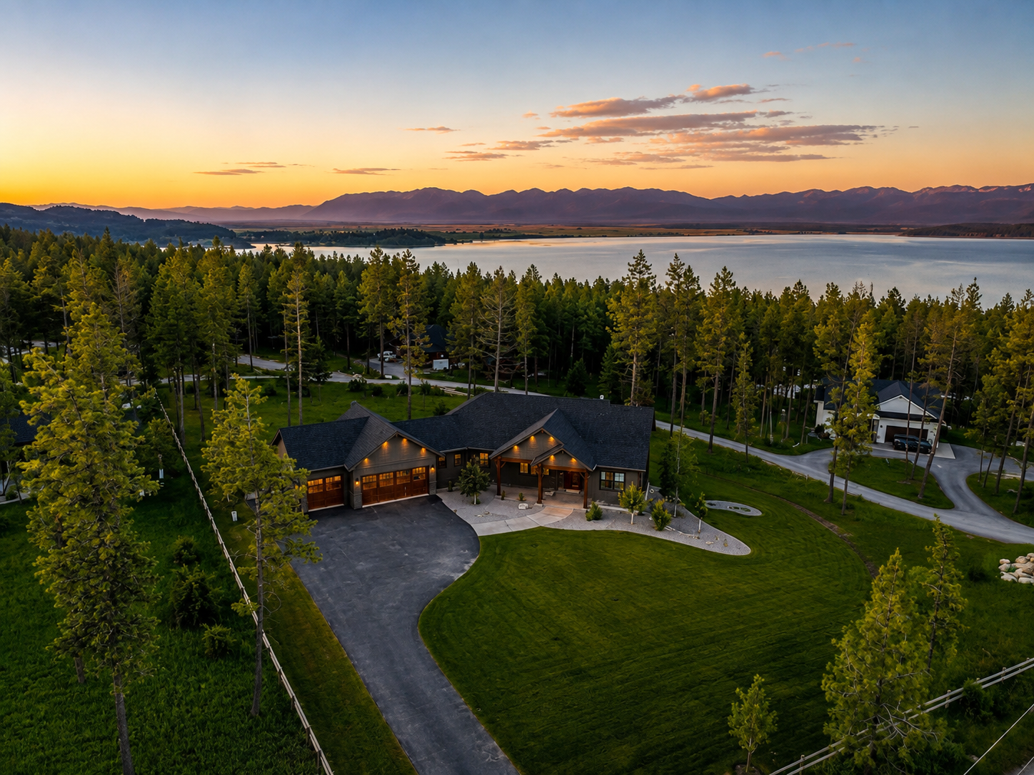 Aerial view of The Evergreen surrounded by pines above Flathead Lake at sunset