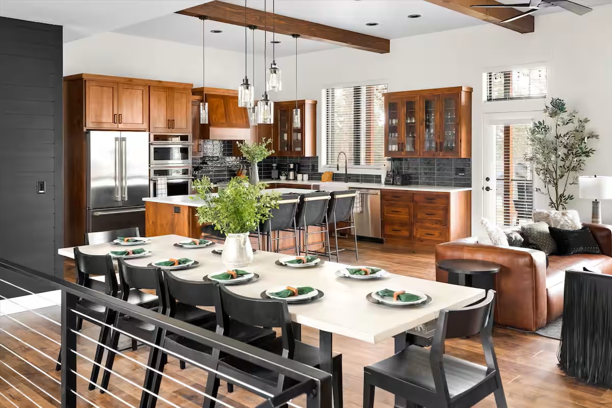 Open kitchen with wood cabinetry, island seating and a long dining table