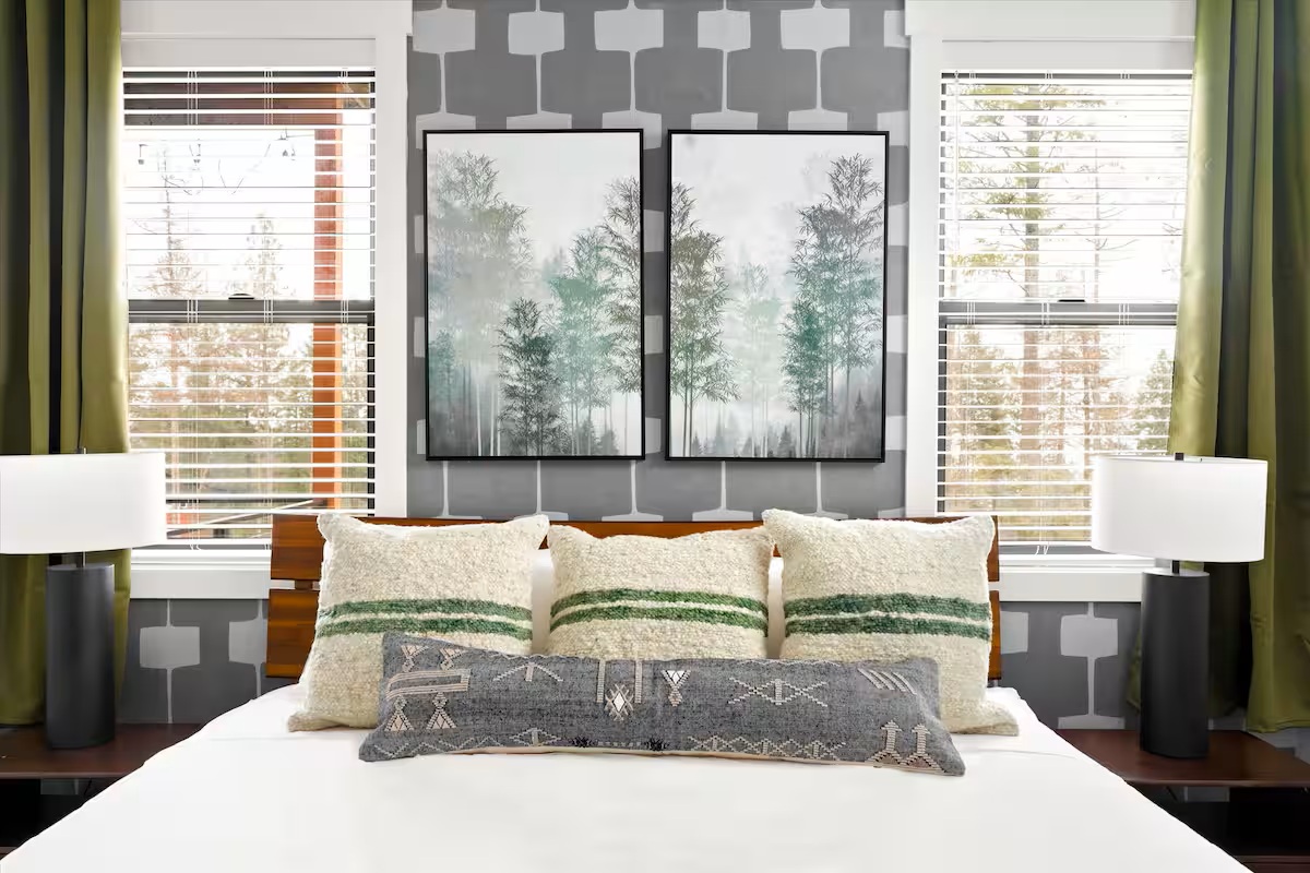 Bedroom with wood headboard, forest artwork and bright windows