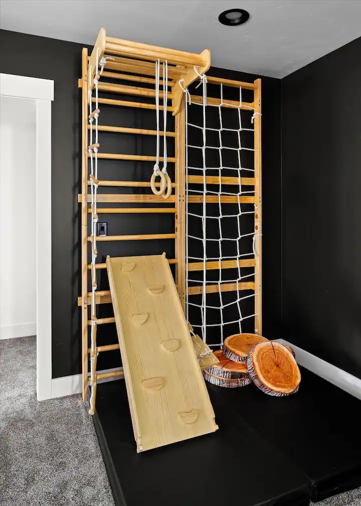 Indoor wooden climbing gym with rings, net and slide