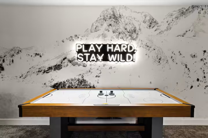 Air hockey table beneath a mountain mural and neon sign
