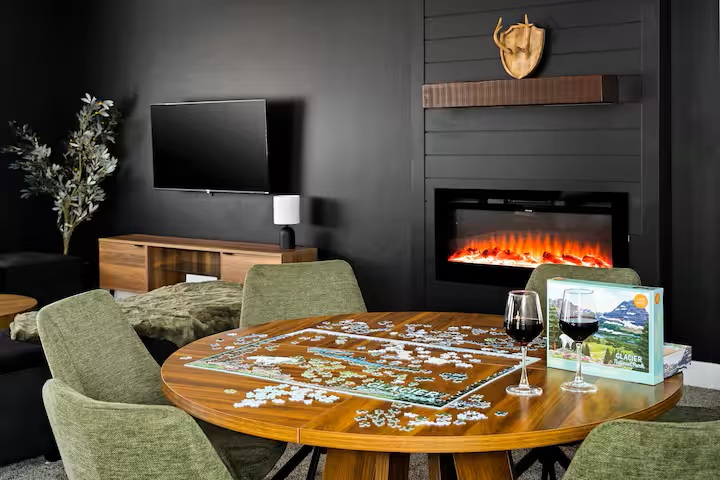 Round puzzle table with green chairs in front of the fireplace