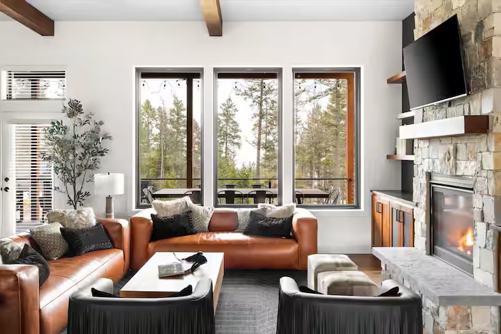 Living room with leather sofas, tall windows and a stone fireplace