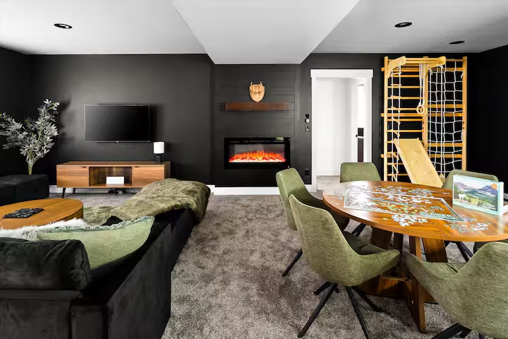 Lower lounge with linear fireplace, TV, round puzzle table and kids climbing gym