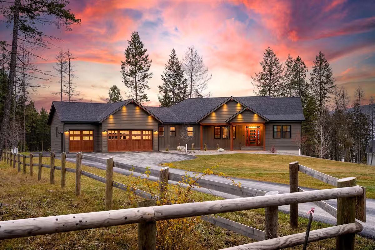 Front of the home at sunset with warm interior lights and a fiery Montana sky