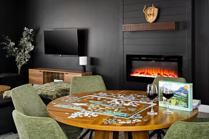 Lounge with linear fireplace, TV and a round puzzle table set with wine