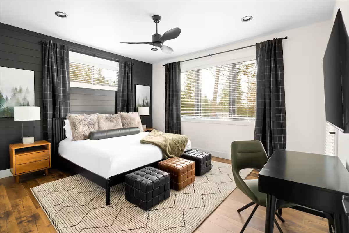 King bedroom with shiplap accent wall, desk and forest views